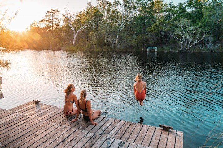 a group of people sitting on a bench next to a body of water