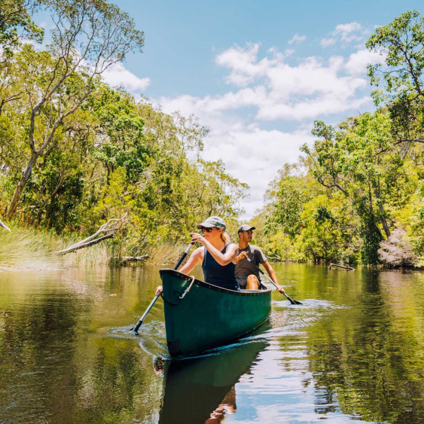 a person riding on the back of a boat next to a lake