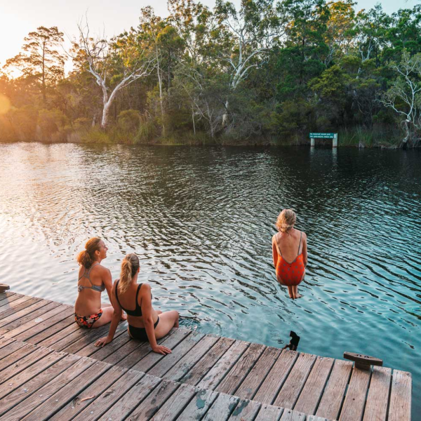 a group of people sitting on a bench next to a body of water
